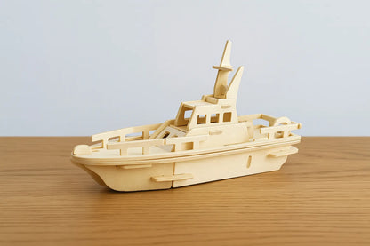 Maquette en bois d’un bateau moderne à deux ponts, posée sur une table en bois devant un mur gris clair.
