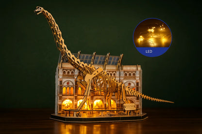 Maquette en bois d’un brachiosaure géant éclairée par des lumières LED chaudes, placée devant une reproduction miniature d’un musée, le tout sur une table en bois.