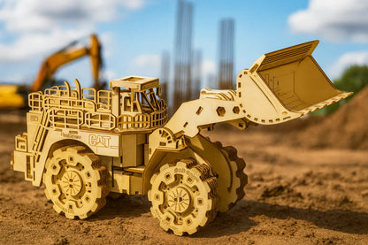 Maquette en bois d’un bulldozer détaillé avec grande pelle avant articulée et pneus crantés, posée sur un chantier de construction sous un ciel bleu.