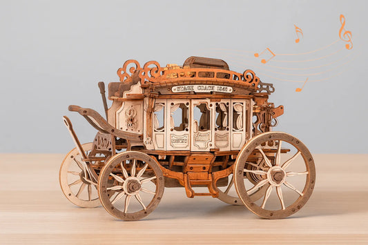 Maquette en bois d’un carrosse musical richement décoré, avec des notes de musique flottant autour, posée sur une table en bois devant un mur gris clair.