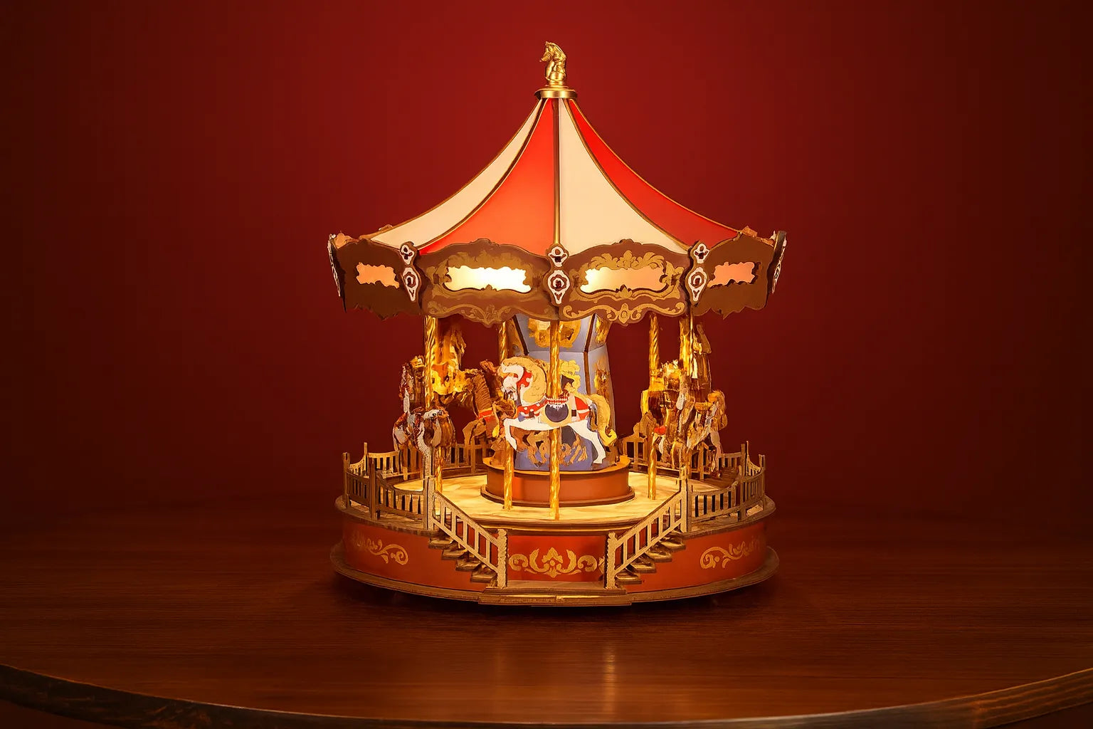 Maquette en bois d’un carrousel coloré avec chevaux posée sur une table en bois devant un mur rouge.
