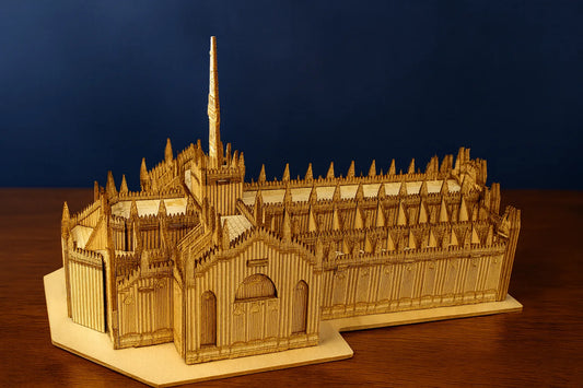 Maquette en bois du Duomo de Milan posée sur une table en bois devant un fond bleu uni.