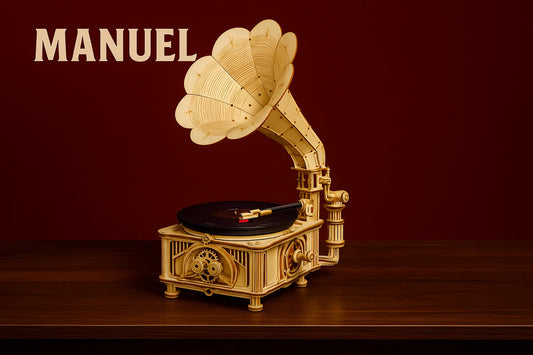 Maquette en bois d'un gramophone posée sur une table en bois devant un fond rouge avec le mot MANUEL écrit en haut à gauche.