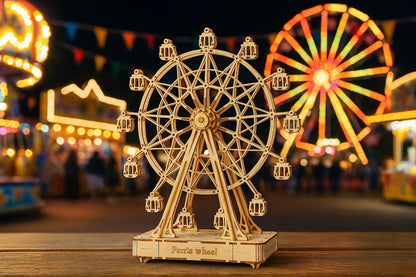 Maquette en bois d’une grande roue posée sur une table en bois avec une fête foraine lumineuse en arrière-plan.