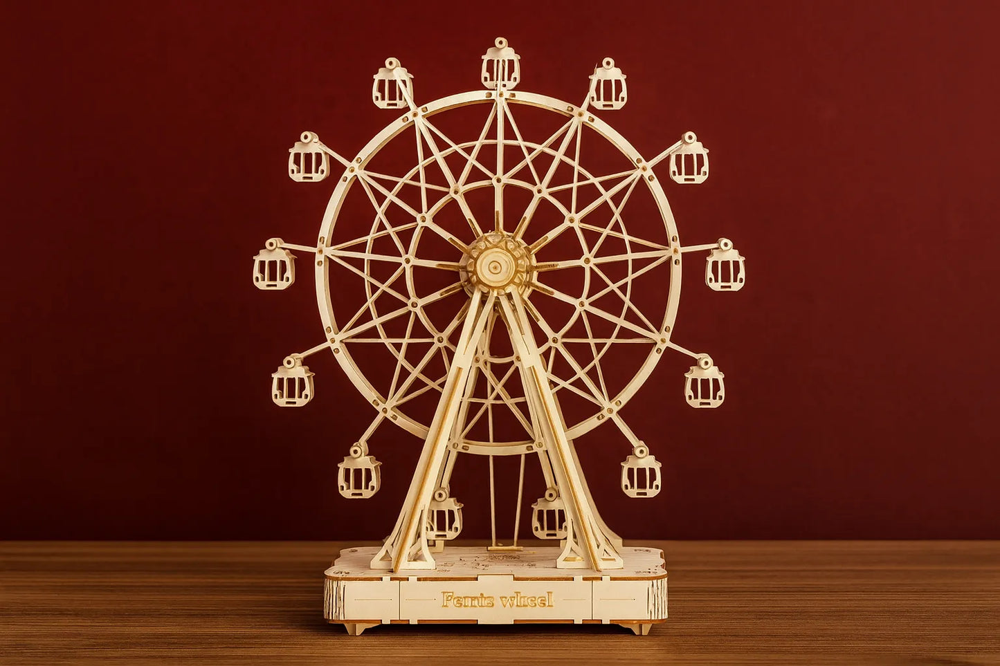 Maquette en bois d’une grande roue posée sur une table en bois devant un mur rouge.