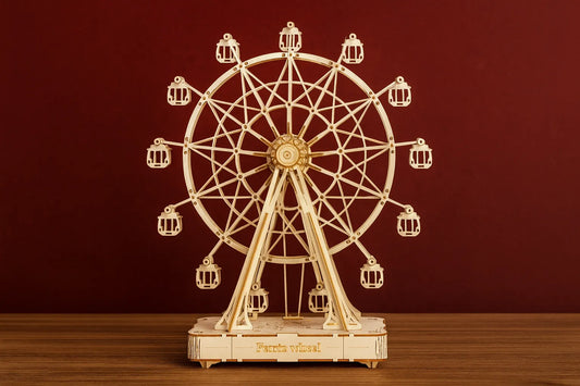 Maquette en bois d’une grande roue posée sur une table en bois devant un mur rouge.
