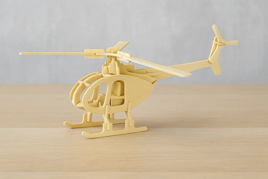 Maquette en bois d’un hélicoptère beige aux pales fines, posée sur une table en bois devant un mur gris clair.