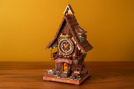 Maquette en bois d’une maison horloge colorée posée sur une table en bois avec un fond jaune uni.