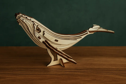 Maquette en bois de baleine finement détaillée, présentée sur une table en bois devant un fond vert.