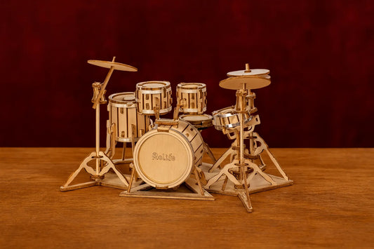 Maquette en bois de batterie posée sur une table en bois avec un fond rouge foncé.