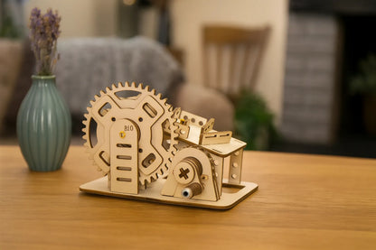 Maquette en bois d’un petit circuit de billes, composée d’engrenages et de rampes, posée sur une table en bois dans un salon à la décoration chaleureuse.