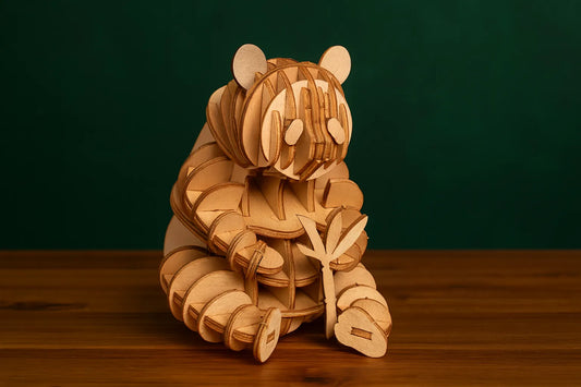 Maquette en bois d’un panda tenant du bambou, présentée sur une table en bois avec un fond vert.