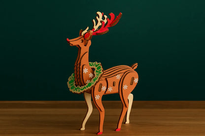 Maquette en bois d’un renne de Noël placée dans un paysage enneigé au coucher du soleil.