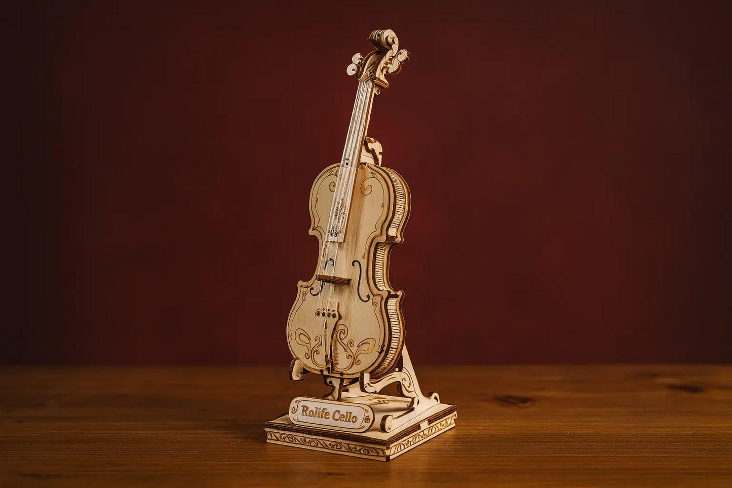 Maquette en bois de violon posée sur une table en bois avec un fond rouge uni.