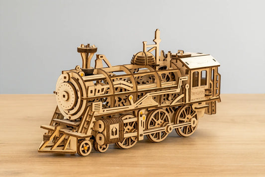Maquette en bois d’une locomotive classique détaillée posée sur une table en bois devant un mur gris clair.