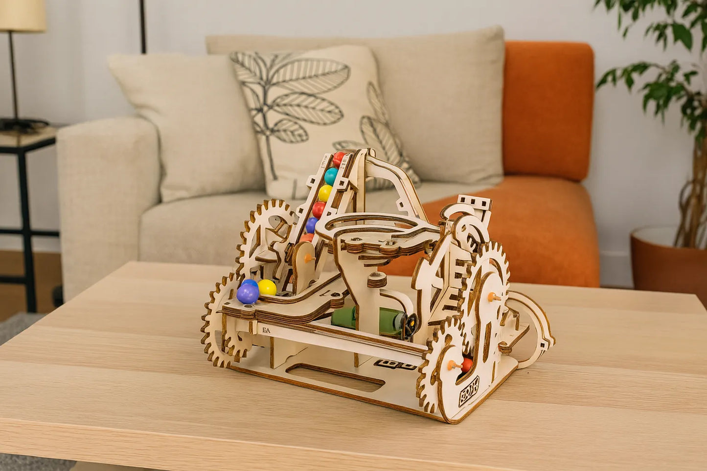 Maquette en bois d’une montée de billes colorées, avec des rampes en boucle, présentée sur une table dans un salon lumineux.