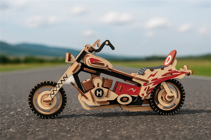 Maquette en bois d’une moto colorée rouge et noire posée sur une route de campagne.