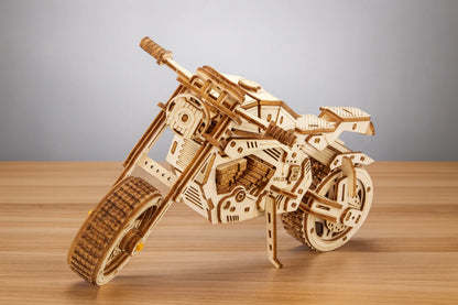 Maquette en bois d’une moto sportive, au design anguleux et mécanique, posée sur une table en bois devant un mur gris clair.