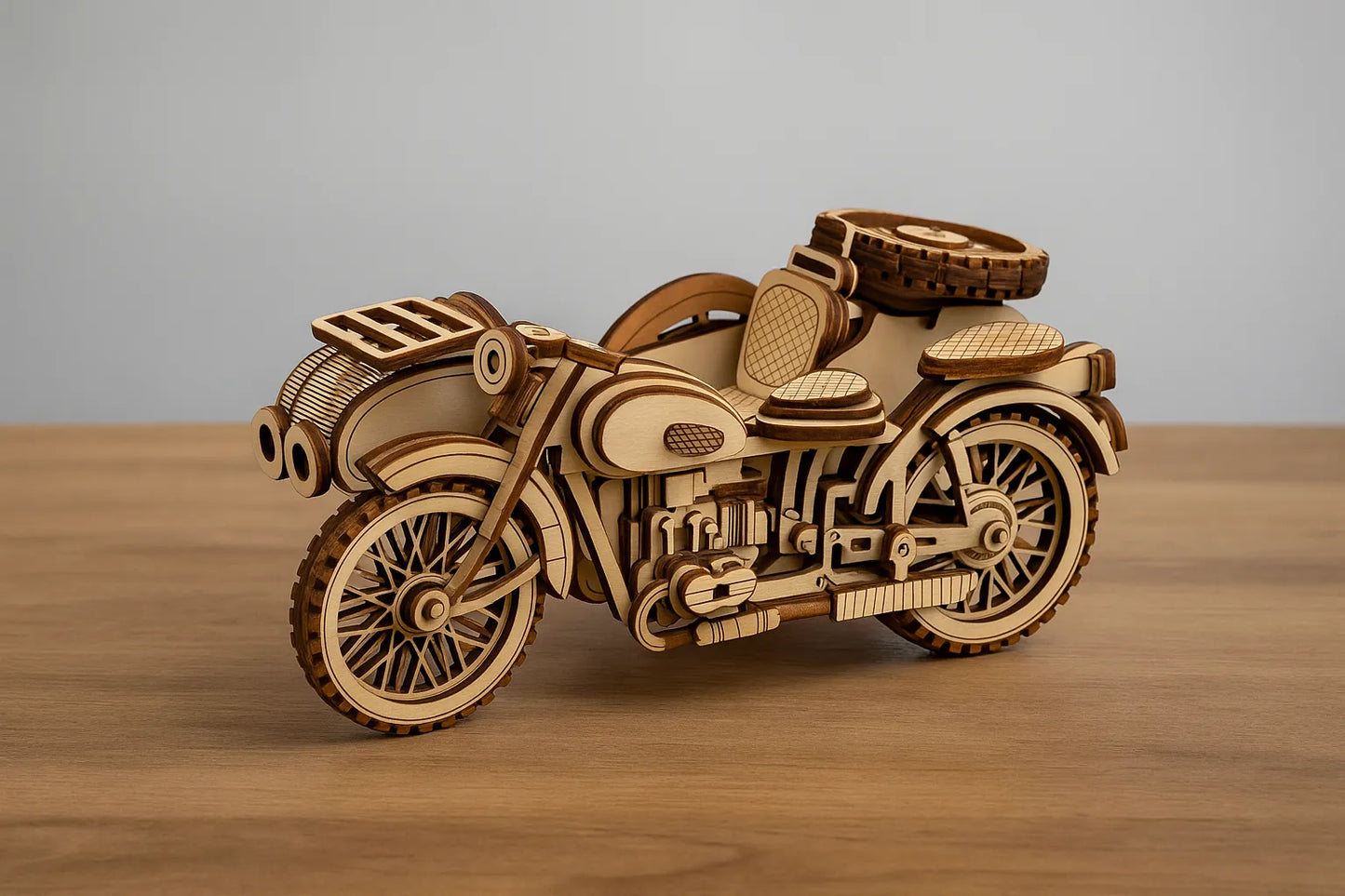 Maquette en bois d’une moto vintage, riche en détails mécaniques et décoratifs, posée sur une table en bois devant un mur gris clair.