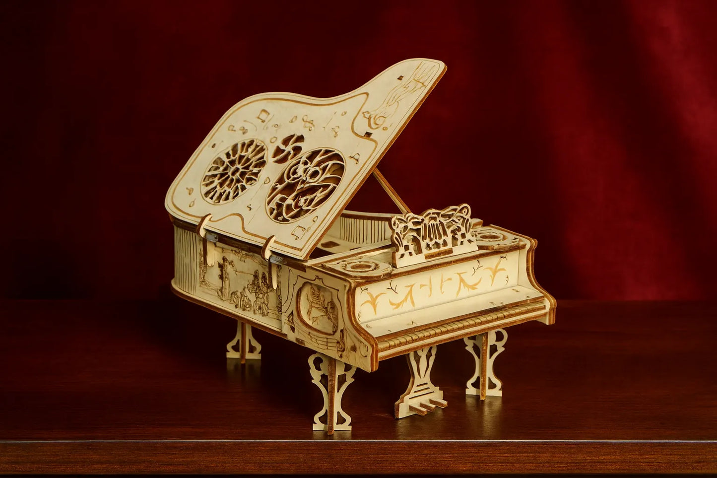 Modèle réduit en bois d’un piano à queue décoratif, finement sculpté et assemblé à la main, sur fond rouge.