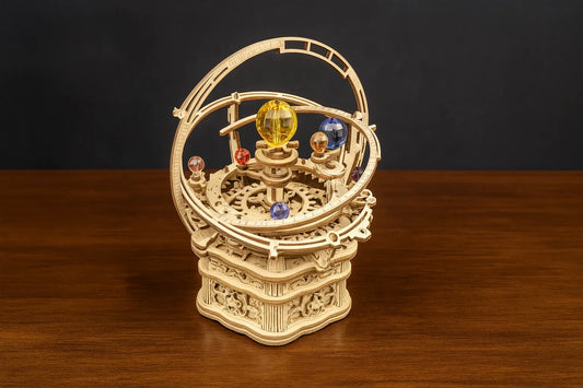 Maquette en bois du système solaire avec sphères en cristal coloré posée sur une table en bois devant un mur gris.