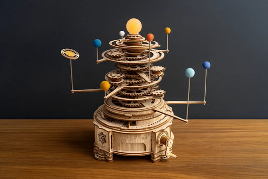 Maquette en bois du système solaire mécanique avec planètes colorées posée sur une table en bois devant un mur gris.