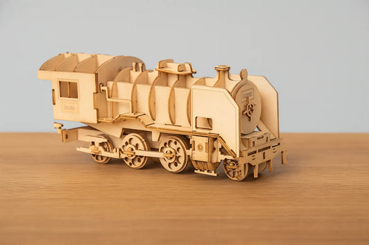Maquette en bois d’un train à vapeur classique avec sa locomotive, placée sur une table en bois devant un mur gris clair.