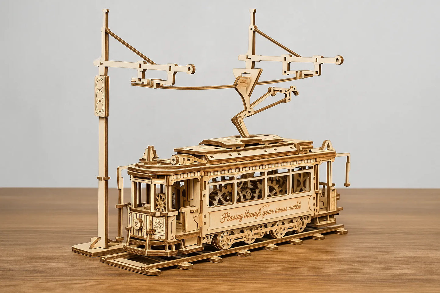 Maquette en bois d’un tramway vintage avec caténaire posée sur une table en bois devant un mur gris clair.