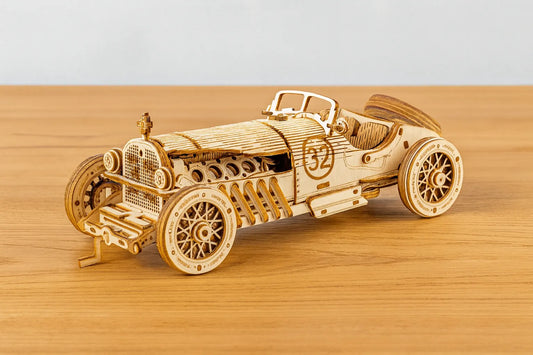 Maquette en bois d’une voiture de course vintage numéro 32, au style rétro, placée sur une table en bois devant un mur gris clair.