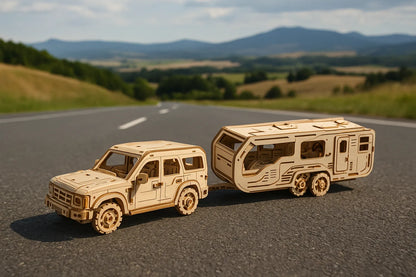 Maquette en bois d’un véhicule tout-terrain tirant une caravane, posée sur une route de campagne avec des montagnes à l’horizon.