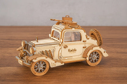 Maquette en bois d’une voiture vintage avec le logo “Rolife” sur la portière et une valise sur le toit, placée sur une table en bois devant un mur gris clair.